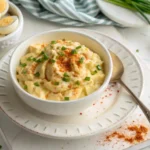 A bowl of keto deviled egg salad garnished with paprika and fresh chives.