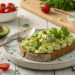 A bowl of creamy avocado egg salad garnished with fresh chives.